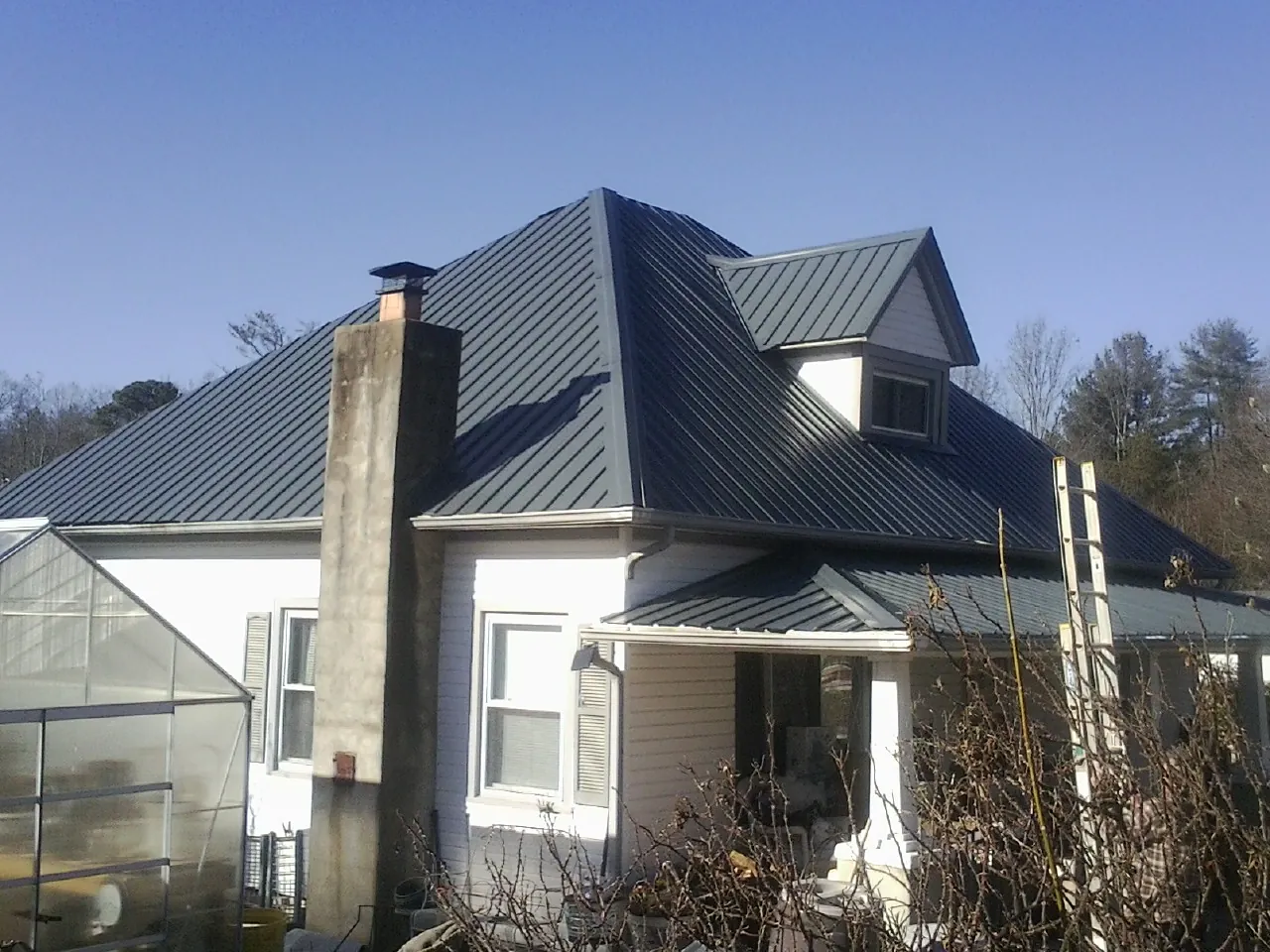 Dark blue standing seam metal roof on a white farmhouse with dormer — Slate & Tile Roof Repair by Roofing Brothers in Painesville