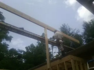Carpenter setting a ridge beam over a new addition frame — Ice Dam Removal by Roofing Brothers in Painesville
