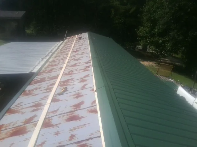 Old rusted panels beside newly installed green metal roofing — Wind Damage Roof Repair by Roofing Brothers in Painesville