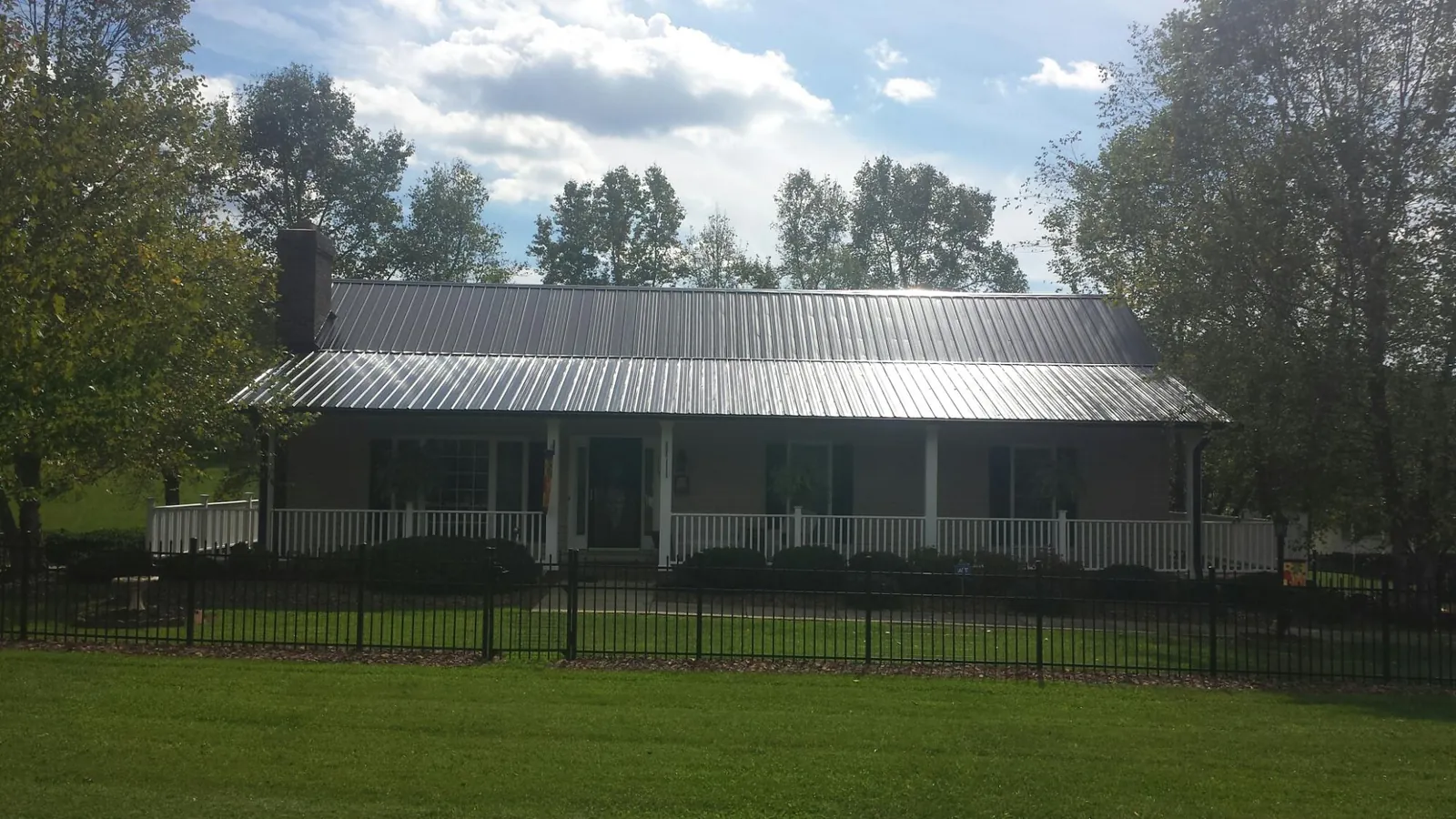 Gray metal roof on a brick ranch with a full width front porch — Gutter Guard Installation work by our crew in Painesville