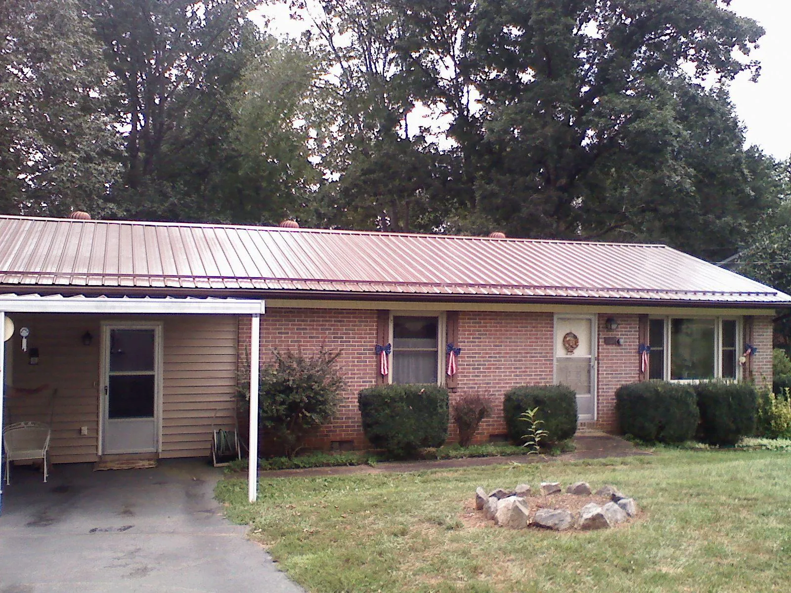 Bronze metal roof and carport on a brick ranch home — Roof Repair work by our crew in Painesville
