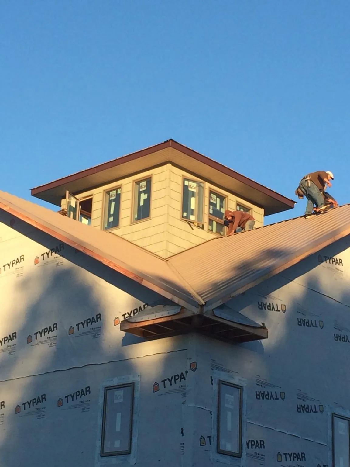 Roofers working around a rooftop cupola on a new metal roof at sunset — Roof Waterproofing in Painesville by Roofing Brothers